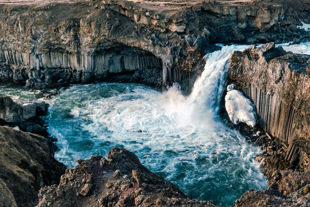 A photo of Aldeyjarfoss, a waterfall in Iceland, surrounded by basalt columns and icy water.