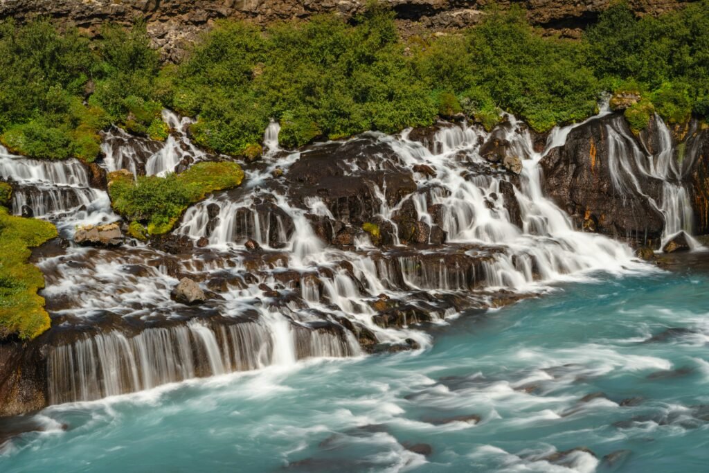 A photo of Hraunfossar, a waterfall in Iceland where water flows through a lava field.